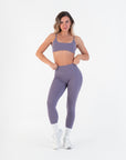 Front view of the High-Rise Leggings in Acai with the model adjusting the waistband