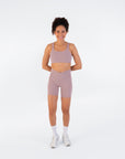Smiling model wearing the Fig Crossover V-Waist Shorts with a matching sports bra