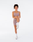 Model stretching in the Fig Crossover V-Waist Shorts and matching sports bra
