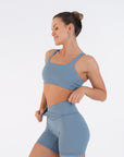 Model wearing the Juniper Racerback Bra while adjusting matching shorts